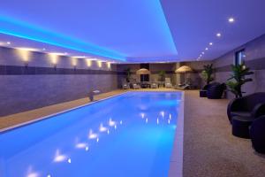 a pool in a hotel lobby with blue lighting at Zenitude Swiss Apparthotels in Ferney-Voltaire