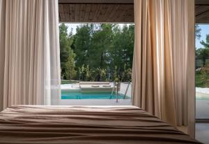 a bedroom with a view of a swimming pool through a window at Domus Gaia Suites in Nikiti