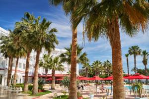 a resort with palm trees and tables and umbrellas at Houda Yasmine Marina & SPA in Hammamet