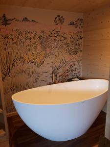 a bath tub in a bathroom with a wall mural at Le chalet du Chardonneret in Soultzbach-les-Bains +17 photos