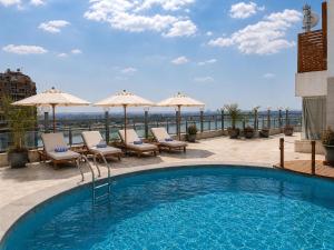 a swimming pool with chairs and umbrellas on a building at Maadi Hotel in Cairo