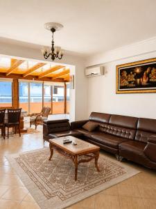 a living room with a leather couch and a table at Terminal Comfort Apartament in Tirana
