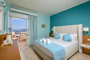 a bedroom with a bed with blue walls and a balcony at Sunny Hotel Thassos in Chrysi Ammoudia +88 photos