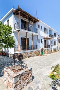 a large white house with a stone wall at Fotini Rooms in Skopelos Town