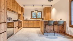 a kitchen with wooden cabinets and bar stools at Chalet Le Savoy in Chamonix +22 photos