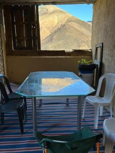 a glass table and chairs on a patio with a view at Berber lodge amssouzart in Tizgui