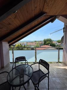 a table and chairs on a balcony with a view of the water at Slavuj in Novi Sad