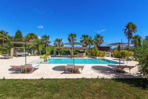 a pool with chairs and umbrellas in a yard at Agriturismo Li Frutti in Otranto
