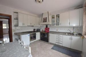 a kitchen with white cabinets and a table in it at Casa Emiliano in Cee