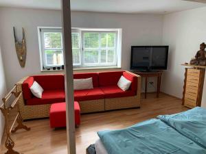 a living room with a red couch and a flat screen tv at Wohnhaus am Marktplatz in Röhrnbach in Röhrnbach
