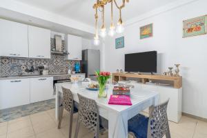 a kitchen with a white table with chairs and a tv at La Casa Di Chloe in Marzamemi