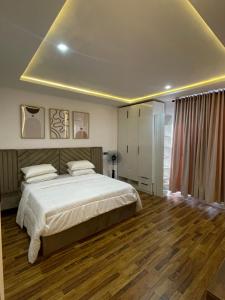 a bedroom with a large white bed and wooden floors at Precious home apartment II in Lekki