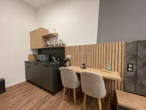 a kitchen with a counter and two white chairs at Apartmenthaus Zeuthen 3 in Zeuthen +2 photos