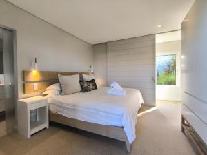 a bedroom with a large white bed and a window at Betty in Plettenberg Bay