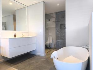 a bathroom with a tub and a sink and a toilet at Betty in Plettenberg Bay +12 photos
