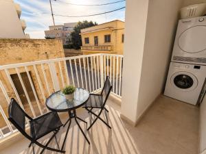 a balcony with a table and chairs and a washing machine at Il Kenn ta Zeppi - Apartment 4 in Qala