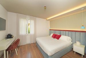 a small bedroom with a bed and a desk at Hotel Unico by Dori in Sirmione