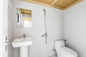 a white bathroom with a toilet and a sink at Savia Home in Danang +25 photos