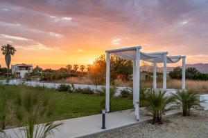 a wedding altar in a field with the sunset in the background at SolMare Premium Suites in Mastihari