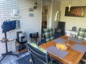 a patio with a wooden table and chairs and a television at Ferienhaus Menkhoff in Dornumersiel