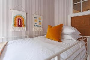 a white bed with an orange pillow on top of it at The Greenhouse Ayr in Ayr