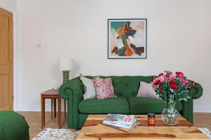 a living room with a green couch and a table with flowers at The Greenhouse Ayr in Ayr +65 photos