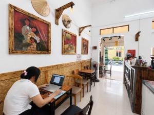 a woman sitting at a table with a laptop at An house Ninh Binh in Ninh Binh