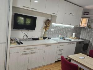 a kitchen with white cabinets and a tv on the wall at Papillon in Visoko
