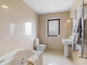 a bathroom with a tub and a toilet and a sink at Calla Lookout in Roundstone +24 photos