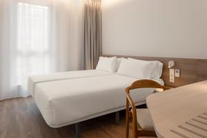 a bedroom with a large white bed and a table at B&B HOTEL Covilhã in Covilhã