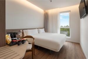 a hotel room with a bed and a desk and a window at B&B HOTEL Covilhã in Covilhã