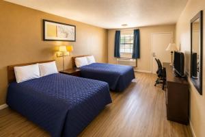 a hotel room with two beds and a flat screen tv at Segovia Lodge Junction TX I -10 in Junction