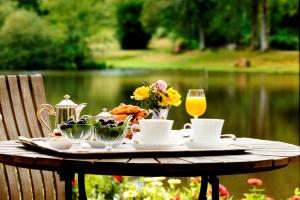 - une table avec un plateau de nourriture et un verre de jus d'orange dans l'établissement Au Moulin de La Gorce, à La Roche-lʼAbeille