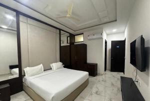 a bedroom with a white bed and a flat screen tv at Hotel Pratap Palace in Bharatpur