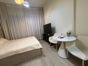 a bedroom with a bed and a table and a tv at Azizi Riviera in Dubai