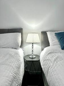 a bedroom with two beds and a table with a lamp at The Alexandria in Westhoughton