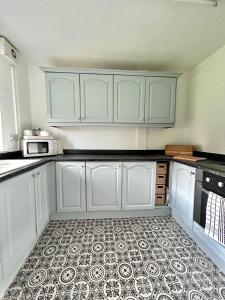 a kitchen with white cabinets and a tile floor at The Alexandria in Westhoughton