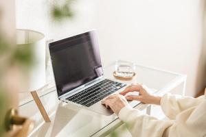 a person typing on a laptop computer on a glass table at Miroku Nagoya in Minami-sotoborichō
