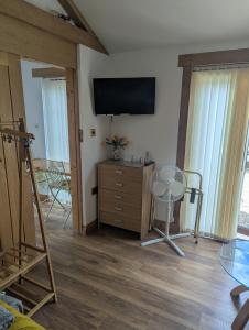 a living room with a television and a dresser with a chair at Sunnyside Annexe in Oxford