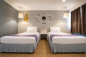two beds in a hotel room with at Sawasdee Siam Pattaya Hotel in Pattaya