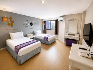 a hotel room with two beds and a desk at Sawasdee Siam Pattaya Hotel in Pattaya