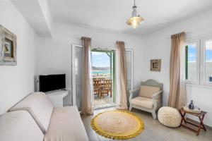 a living room with a couch and a tv and a window at Salty Wind Antiparos Apartments and Studios in Agios Georgios