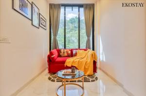 a living room with a red couch and a table at EKOSTAY - ONYX Villa in Mumbai