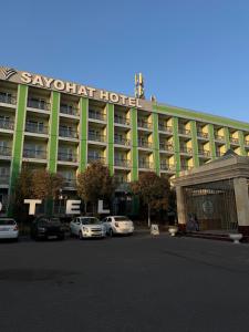 a large hotel with cars parked in front of it at Sayohat Hotel in Tashkent