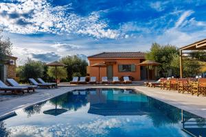 a swimming pool with chairs and a house at Penelopes Rhapsody Resort in Missolonghi