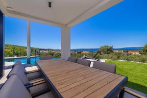 a dining room with a wooden table and chairs at Luxury villa 45 with infinity pool in Punat