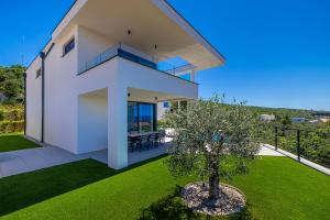 a white house with a tree in a yard at Luxury villa 45 with infinity pool in Punat