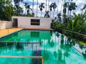 a swimming pool with turquoise water and palm trees at Wayanad Farm Heritage in Sultan Bathery