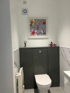 a bathroom with a toilet and a picture on the wall at The Welcome Haven - Cozy Studio with Patio & Free Parking in Chislehurst