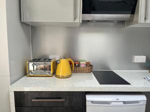 a kitchen counter with a yellow tea kettle and a toaster at The Welcome Haven - Cozy Studio with Patio & Free Parking in Chislehurst